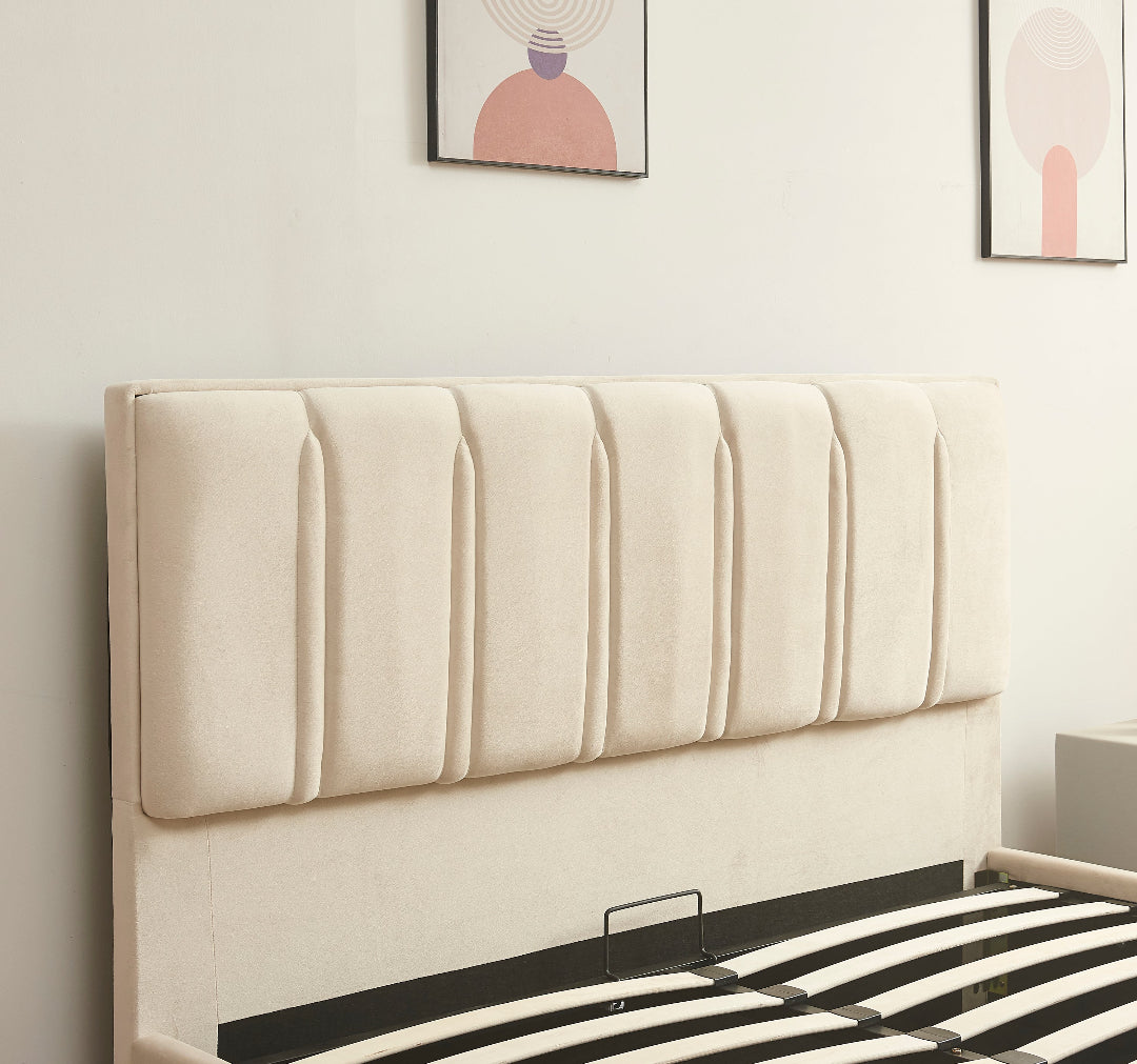 Beige upholstered headboard on a bed with striped bedding, framed artwork on the wall.