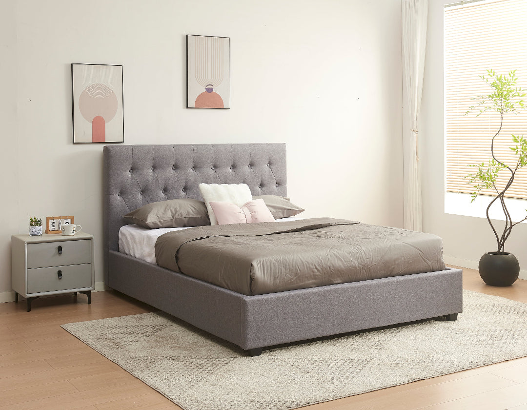 Gray upholstered bed in a bedroom with a nightstand and decor.