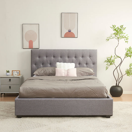Gray upholstered bed in a room with a nightstand, plant, and wall art.